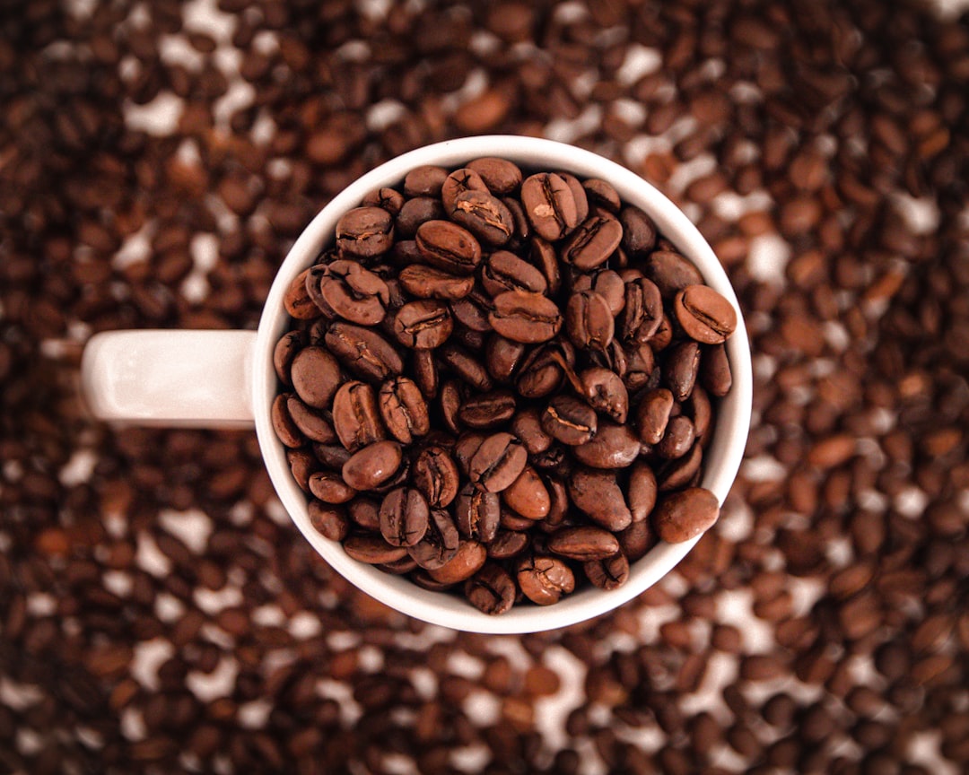 a-cup-filled-with-coffee-beans-on-top-of-a-table-d6eroyavcy4